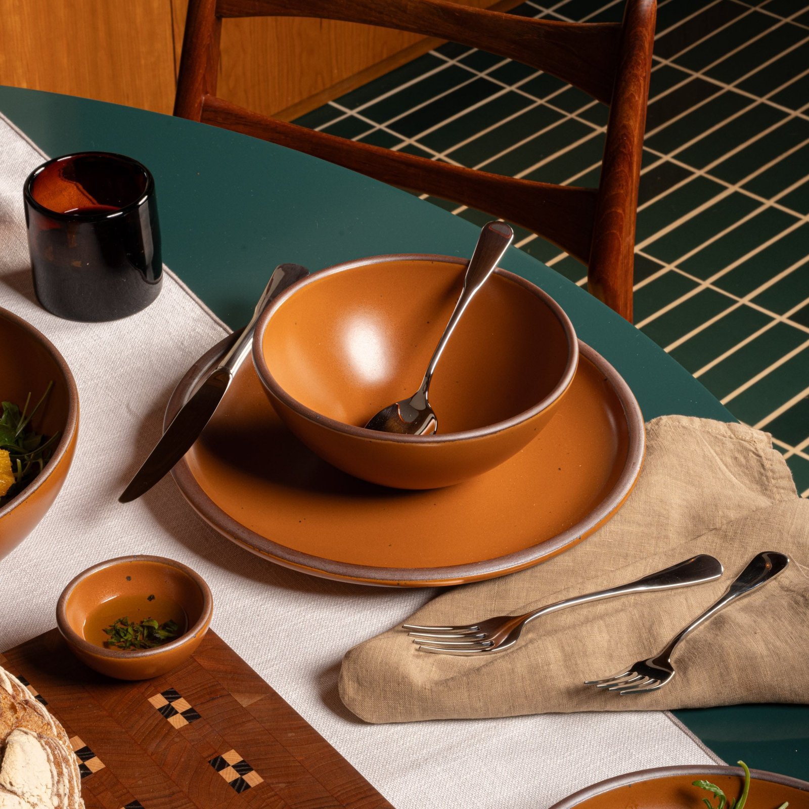 Vellax Supply soup bowl in Ember, in a table setting with other dinnerware